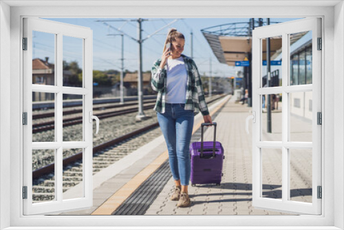 Happy woman using mobile phone on a train station.