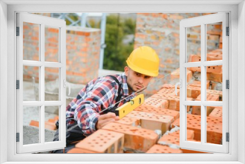 Fototapeta Naklejka Na Ścianę Okno 3D - Installing brick wall. Construction worker in uniform and safety equipment have job on building
