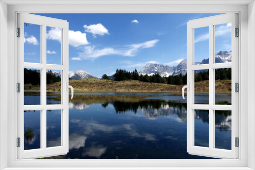 Fototapeta Naklejka Na Ścianę Okno 3D - Alp mountains reflecting at a lonesome lake with blue cloudy sky