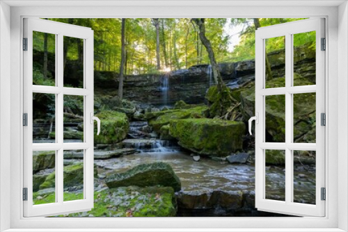 Fototapeta Naklejka Na Ścianę Okno 3D - Beautiful view of water flowing down the rocks covered in moss in the forest.