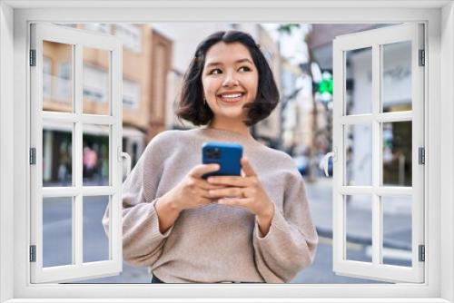 Young woman smiling confident using smartphone at street