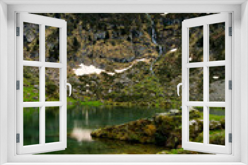 Fototapeta Naklejka Na Ścianę Okno 3D - View on the beautiful blue lake of Ayes, with a waterfall, the pastures and the peaks of the French Pyrenees on a cloudy day in the background