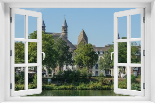 Fototapeta Naklejka Na Ścianę Okno 3D - Beautiful view of the Maas river surrounded by trees and old buildings in Maastricht, Netherlands.