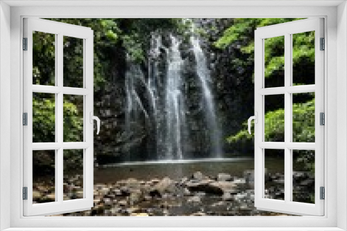 Fototapeta Naklejka Na Ścianę Okno 3D - Vertical shot of a beautiful waterfall coming down the rocky cliff in the middle of a green forest