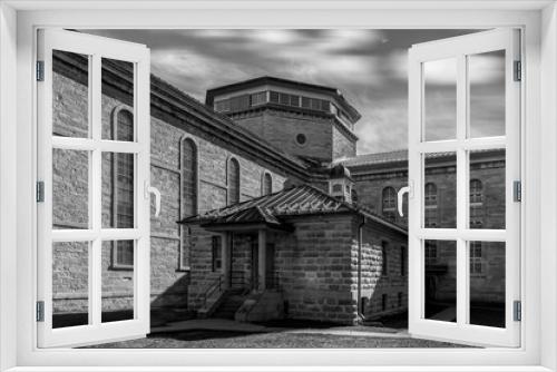 Fototapeta Naklejka Na Ścianę Okno 3D - Exterior view of two large limestone penitentiary cell blocks meeting at a central guard post, high barred windows, high key black and white, nobody