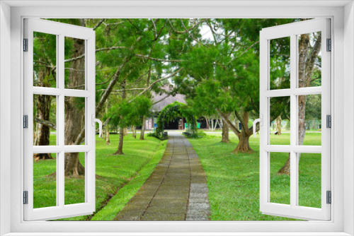 Fototapeta Naklejka Na Ścianę Okno 3D - A walkway in a garden made of brick traverses the edge and amidst lawn or meadow in a flower garden. 
Tourist, travel, holiday and vacation spot Taman Bunga Nusantara, Cianjur, Indonesia