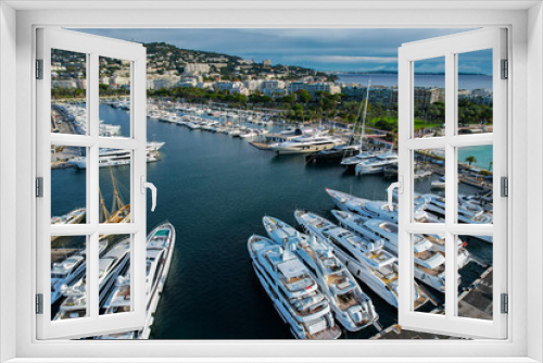 Fototapeta Naklejka Na Ścianę Okno 3D - Aerial view of the marina of Cannes full of Yachts with la Croisette and La Plage Du Festival in the background
