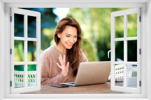 Attractive brunette haired woman sitting outdoor at home and using a laptop