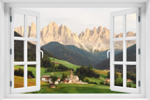 Fototapeta Naklejka Na Ścianę Okno 3D - Stunning view of the Funes Valley (Val di Funes) with the Santa Maddalena Church and the mountain range of the Puez Odle Nature Park in the distance during a beautiful sunset...