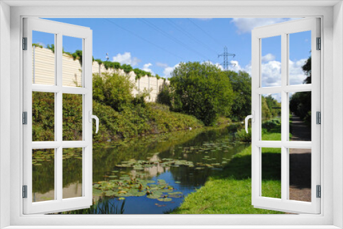 Fototapeta Naklejka Na Ścianę Okno 3D - View of Overgrown Rural Canal with Towpath and Blue Sky 