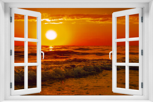 Fototapeta Naklejka Na Ścianę Okno 3D - The sun is sinking into the sea. The sun's rays pass through the waves, smoothly rolling over each other. A bright orange sunset over the sea is large.the concept of a romantic summer vacation.tourism