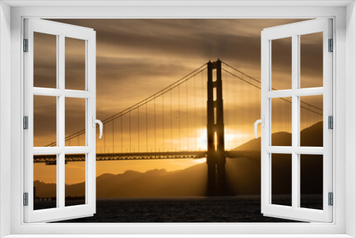 Fototapeta Naklejka Na Ścianę Okno 3D - Golden gate bridge at sunset with a yellow., gold, brown and black sky and Marin County shown to the right. 