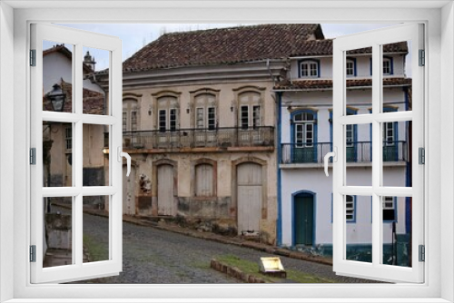 Fototapeta Naklejka Na Ścianę Okno 3D - 
Street with facade of historic townhouses in the city of Ouro Preto, Minas Gerais, UNESCO cultural heritage. Street with old two-story houses in Portuguese colonial style, arched windows and doors, c