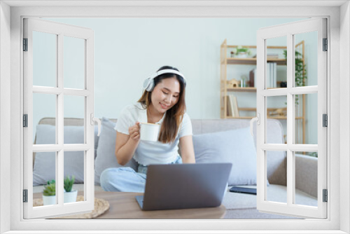 asian teenage girl using computer and wearing headphones at sofa