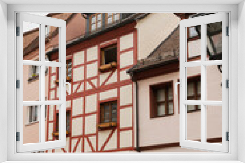 Fototapeta Naklejka Na Ścianę Okno 3D - Old historic architecture in Nuremberg, Germany. Traditional European old town buildings with wooden windows, shutters and colourful pastel walls. Aesthetic summer vacation, tourism background