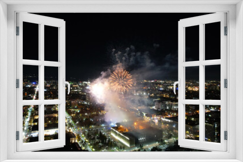 Fototapeta Naklejka Na Ścianę Okno 3D - Huge bright flashes from fireworks in the city center. Aerial view from a drone on the night city of Almaty, colored lights and lanterns. People are resting. Cars are coming. A holiday in the city
