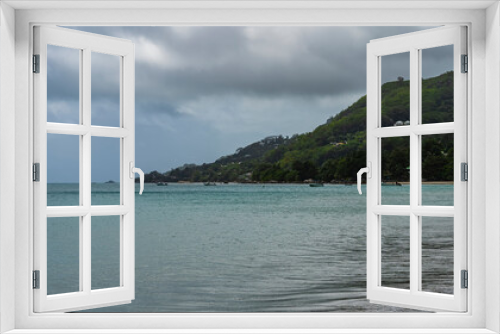 Fototapeta Naklejka Na Ścianę Okno 3D - Serene seascape. The turquoise ocean is calm. Boats are visible on the surface of the water. A green hill against the sky and clouds. Seychelles. Mahe
