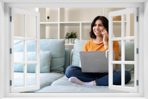 Remote Business. Arab Woman Talking On Phone And Using Laptop At Home