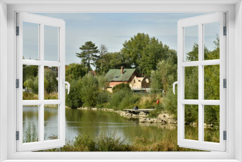 Fototapeta Naklejka Na Ścianę Okno 3D - Le lac principal et sa végétation luxuriante dissimulant plusieurs maisons derrière elle au parc du Paradis à Braine l'Alleud 