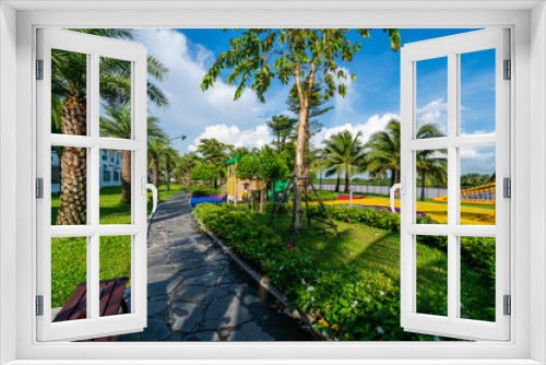 Fototapeta Naklejka Na Ścianę Okno 3D - Public green park with modern blocks of flats and blue sky with white clouds in Vietnam