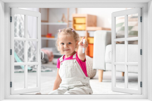 Cute little girl with felt-tip pens sitting on floor at home