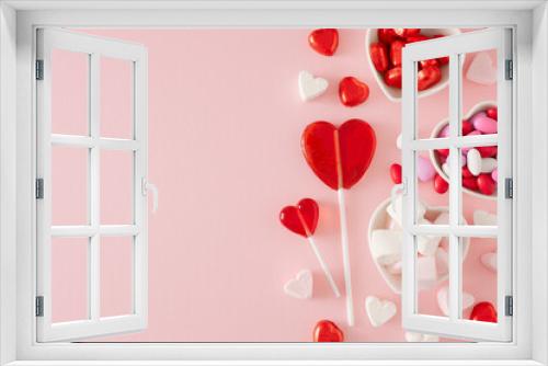 Love Valentines concept. Creative composition made of heart shaped saucers with chocolate candies, lollipops and marshmallow on pastel pink background. Flat lay with copy space.
