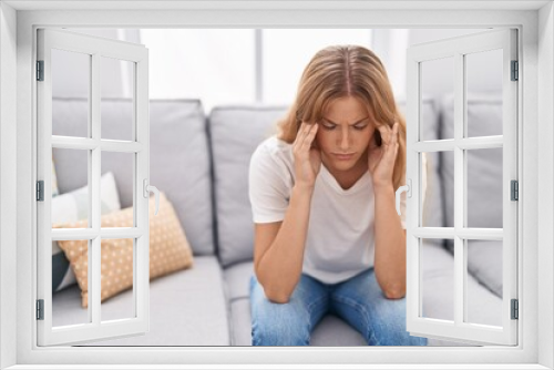 Young blonde girl stressed sitting on sofa at home