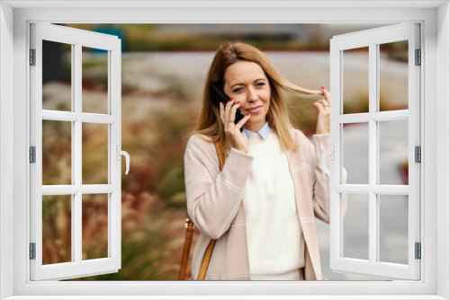 A blond woman is walking and having phone conversation on a street downtown.