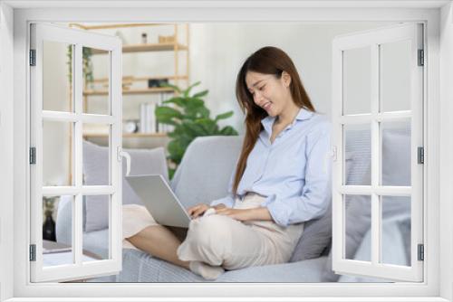 Woman using laptop to work or do homework at home with smiling face in her living room, Creating happiness at work with a smile, Live performance or video call with laptop, Work from home.