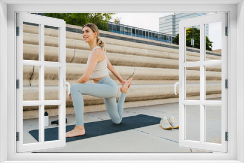 Young woman doing stretching exercises outdoors at city street