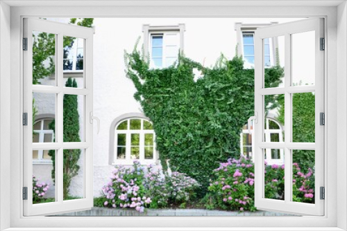 Fototapeta Naklejka Na Ścianę Okno 3D - Ivy covered entrance to white painted brick house with beautiful flower garden and wreath and arched windows