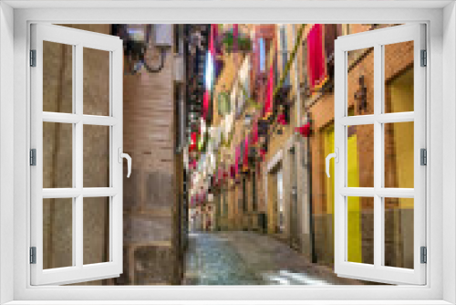 Fototapeta Naklejka Na Ścianę Okno 3D - Narrow alleys of Toledo with shade cover, decorated balconies and sunbeams