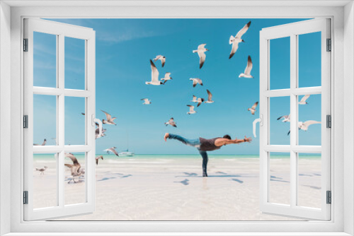 Fototapeta Naklejka Na Ścianę Okno 3D - Man practicing yoga on the beach surrounded by seagulls
