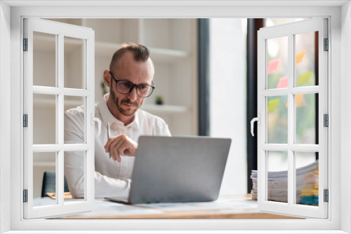 Businessman using laptop computer in office. Happy middle aged man, entrepreneur, small business owner working online.