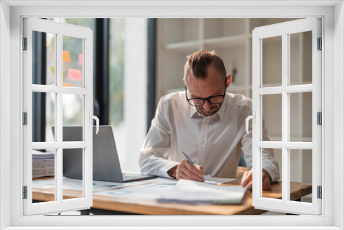 Businessman using laptop computer in office. Happy middle aged man, entrepreneur, small business owner working online.