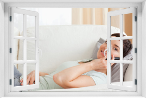 Close up of a calm brunette making a phone call while lying on a