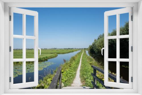 Fototapeta Naklejka Na Ścianę Okno 3D - Typical Dutch rural scenery showing the flat Netherlands. canal water is part of a flood management system for the polder which is land reclaimed from the sea and converted into arable farm fields