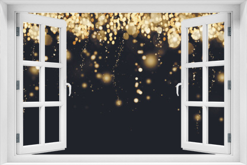 Golden particles border, falling glittering gold sparkles on black background, blurry festive lights, Christmas banner design, copy space
