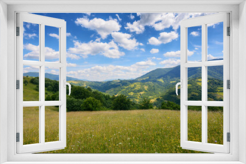 Fototapeta Naklejka Na Ścianę Okno 3D - a picturesque mountainous countryside scene featuring a serene meadow and lush green pastures. the vast grassy fields stretch out under the bright summer sky, creating a stunning landscape