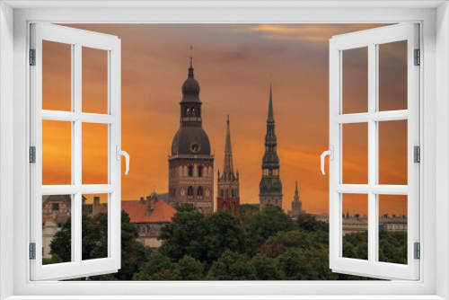 Fototapeta Naklejka Na Ścianę Okno 3D - View of the church towers of the old town of Riga. Orange sky at sunset