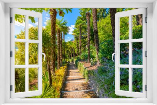 Fototapeta Naklejka Na Ścianę Okno 3D - View from a lush walking path and garden in the lakefront village of Varenna, Italy, on the shores of Lake Como.	 