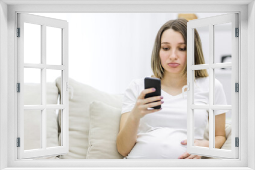 Photo of sad pregnant woman looking in the phone.