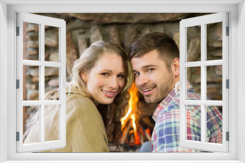 Smiling young couple in front of lit fireplace