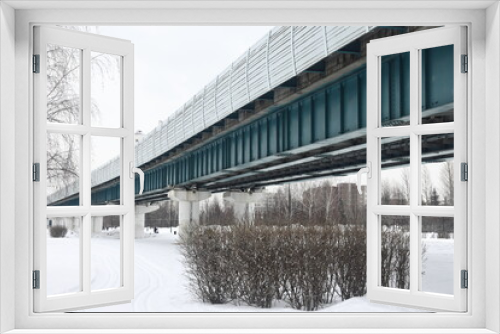 Fototapeta Naklejka Na Ścianę Okno 3D - Winter landscape with a road and trees in the city against the background of the surface metro, houses on the outskirts of Moscow in winter, Butovo residential area, March 2023.