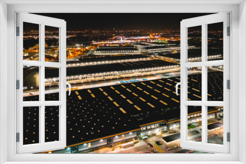 Fototapeta Naklejka Na Ścianę Okno 3D - Aerial view of a warehouse of goods at night. Aerial view of the logistics center. Brightly lit trailers and trucks in a warehouse parking lot
