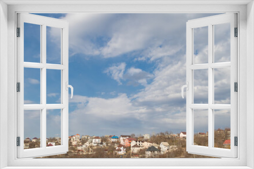 Fototapeta Naklejka Na Ścianę Okno 3D - Panorama of houses on a hill against a blue sky with clouds