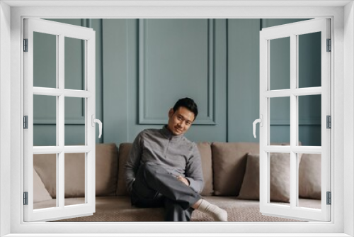 Asian man in fleece sitting in the living room in cold weather.