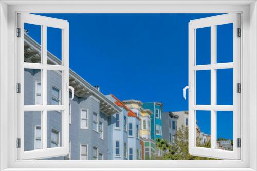 Fototapeta Naklejka Na Ścianę Okno 3D - Colorful homes with panelled walls against blue sky in San Francisco California. Exterior view of beautiful multi-storey houses at a residential neighborhood on a sunny day.