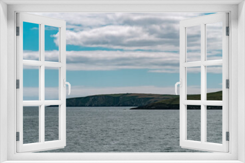 Fototapeta Naklejka Na Ścianę Okno 3D - Blue sky with white clouds over the hilly coast of Ireland. Seaside landscape on a sunny day. Body of water near mountains under white clouds and blue sky