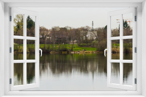 Fototapeta Naklejka Na Ścianę Okno 3D - City park with cranes symmetrically reflected in lake water